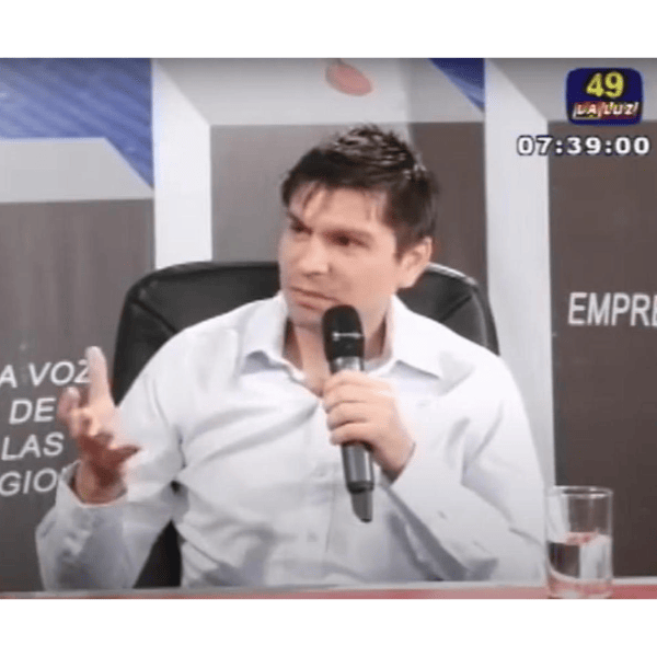 Hombre hablando en programa de televisión con micrófono.